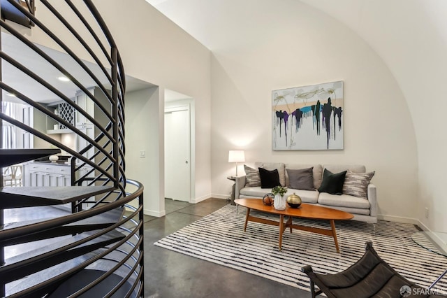 living room featuring stairway, baseboards, a high ceiling, and concrete flooring