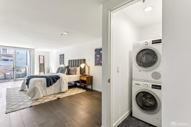 laundry room featuring laundry area, stacked washing maching and dryer, baseboards, and dark wood-type flooring