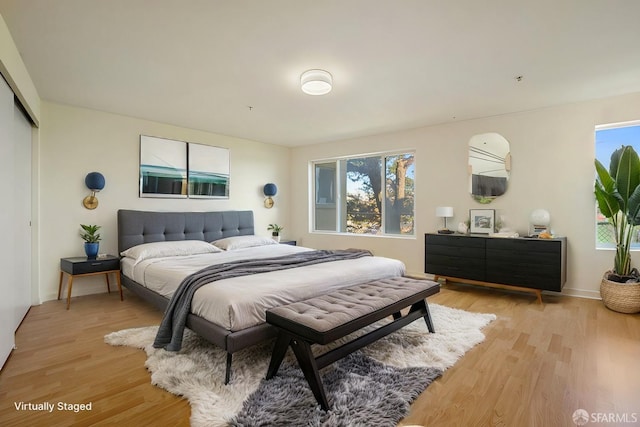 bedroom featuring light wood-type flooring, a closet, and multiple windows