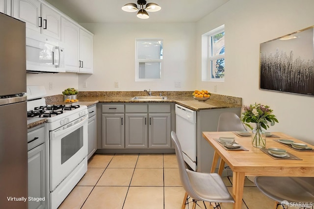 kitchen featuring white appliances, gray cabinets, dark stone counters, light tile patterned flooring, and sink