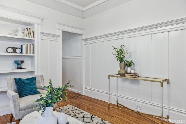 living area with ornamental molding, hardwood / wood-style floors, and built in features