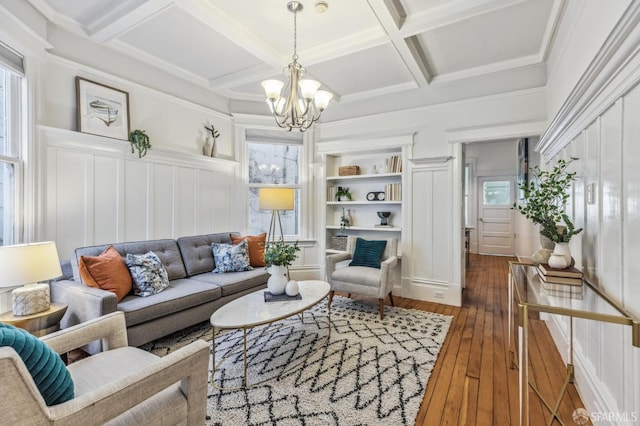 living room featuring dark hardwood / wood-style flooring, coffered ceiling, an inviting chandelier, and plenty of natural light