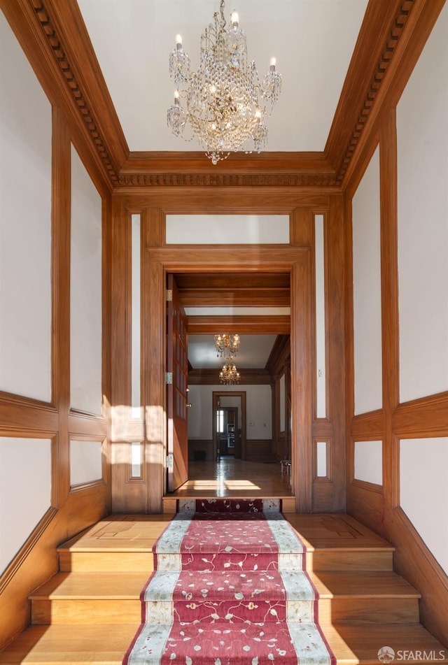 hall with crown molding and a chandelier