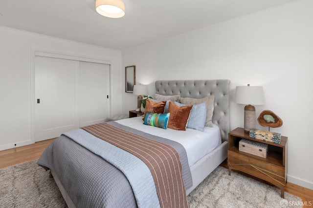 bedroom with wood finished floors, a closet, and baseboards
