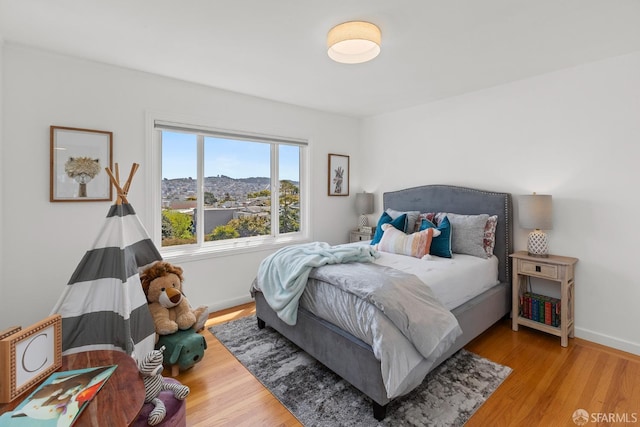 bedroom with wood finished floors, baseboards, and a mountain view
