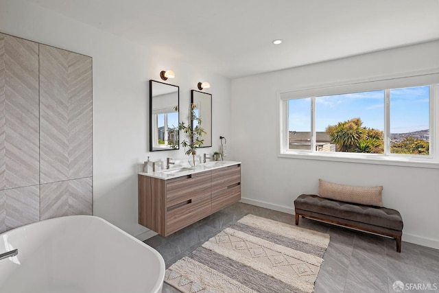 bathroom with a freestanding bath, double vanity, baseboards, and recessed lighting