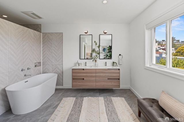 full bath featuring double vanity, plenty of natural light, a freestanding bath, baseboards, and recessed lighting