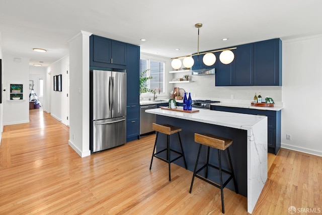 kitchen featuring appliances with stainless steel finishes, blue cabinetry, a sink, a kitchen breakfast bar, and recessed lighting