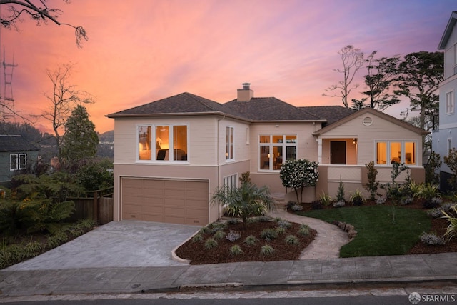 view of front of property with an attached garage, fence, concrete driveway, a lawn, and a chimney