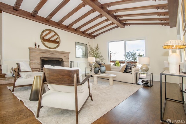 living room with vaulted ceiling with beams, a brick fireplace, and hardwood / wood-style flooring