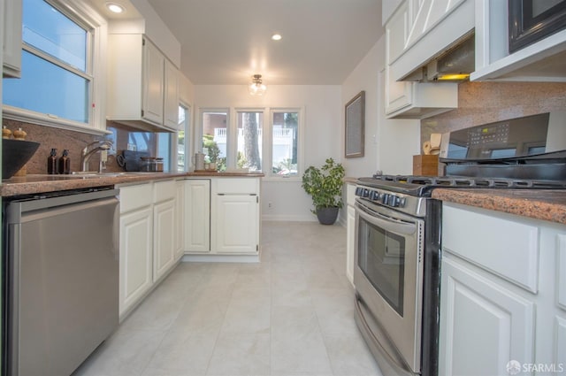 kitchen with white cabinets, appliances with stainless steel finishes, backsplash, custom exhaust hood, and a sink