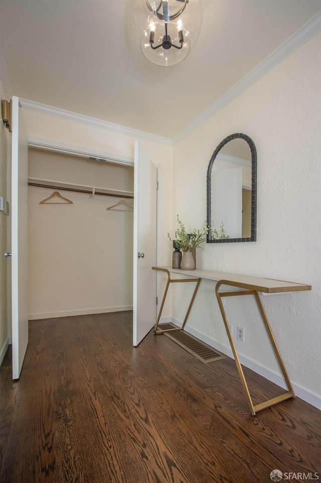 interior space featuring crown molding, a closet, wood finished floors, a chandelier, and baseboards