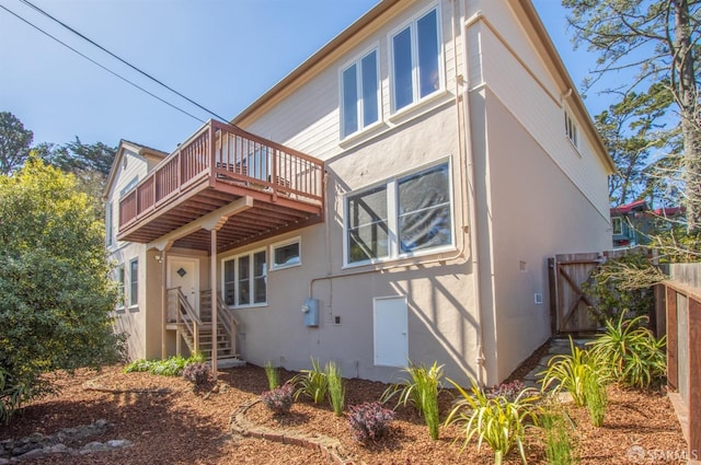 rear view of house with fence and stucco siding