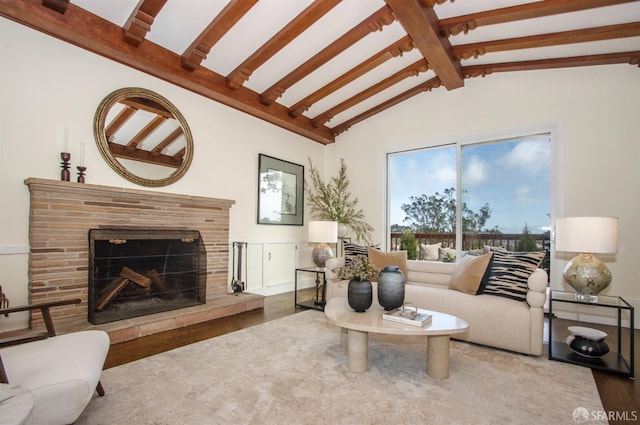 living area with vaulted ceiling with beams, a brick fireplace, and wood finished floors