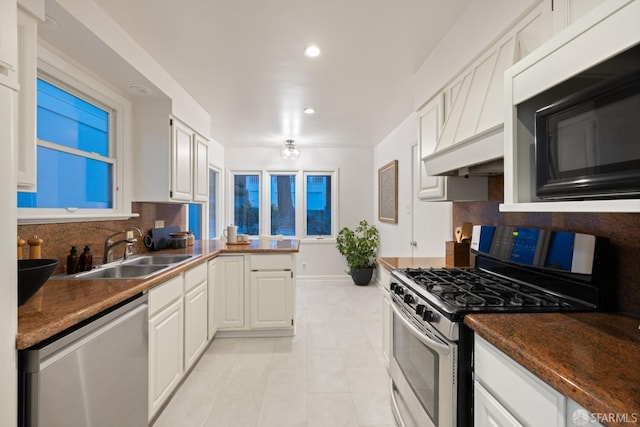 kitchen featuring stainless steel appliances, backsplash, a sink, and white cabinetry