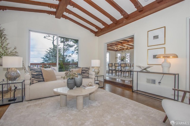 living room with visible vents, lofted ceiling with beams, and wood finished floors