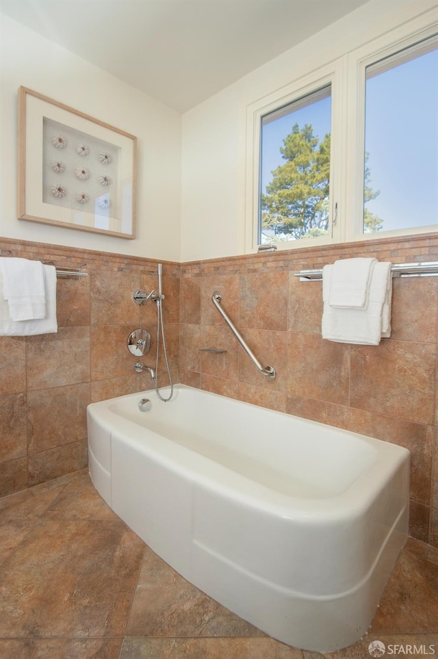 bathroom with wainscoting, a garden tub, and tile walls