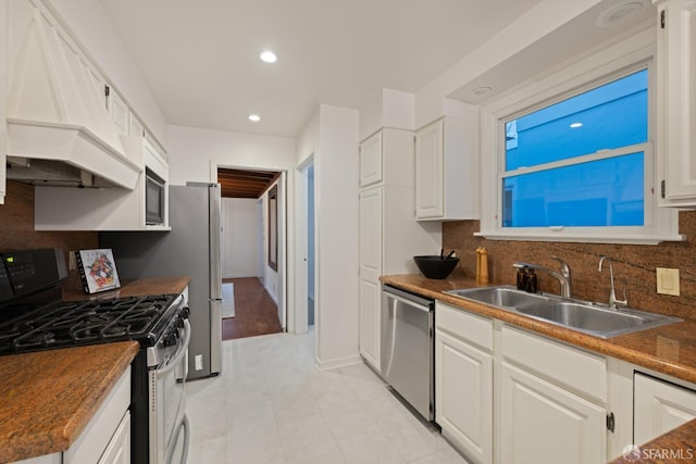 kitchen featuring tasteful backsplash, dark countertops, custom range hood, stainless steel appliances, and a sink