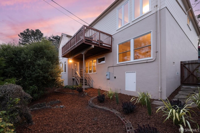 back of property at dusk featuring stucco siding