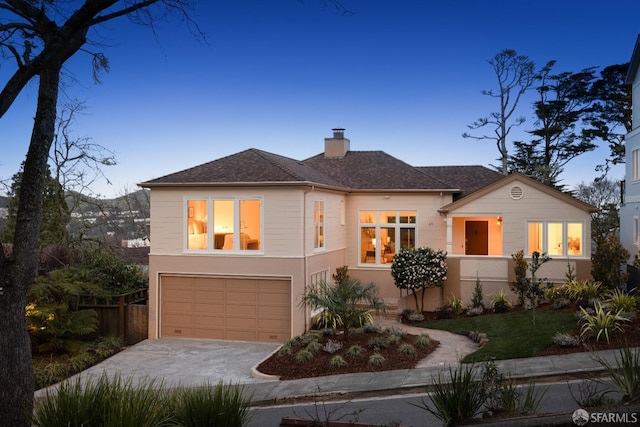 view of front of home featuring driveway, a chimney, an attached garage, and fence