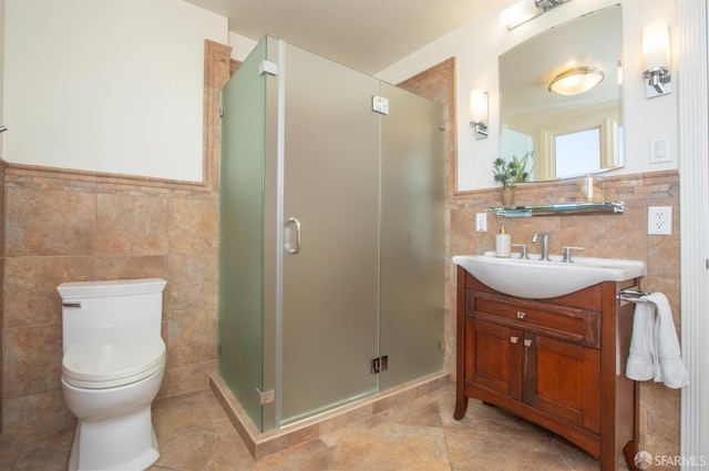 bathroom with vanity, a shower stall, toilet, and tile walls