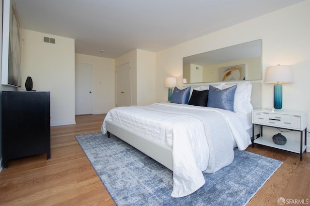 bedroom with light wood-style floors, baseboards, and visible vents