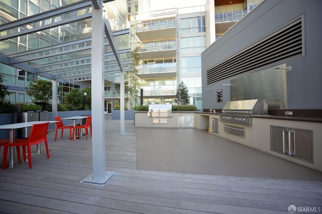 wooden terrace with a grill, area for grilling, and an outdoor bar