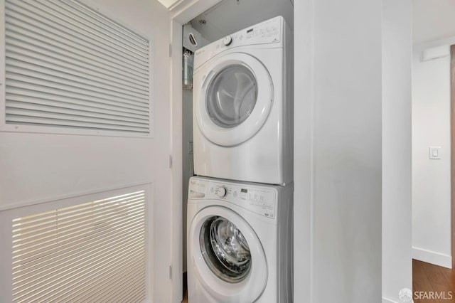 clothes washing area with stacked washer / drying machine and dark hardwood / wood-style flooring