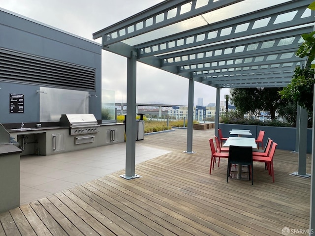 deck with a pergola, an outdoor kitchen, and area for grilling