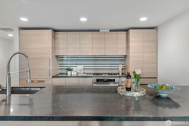 kitchen with decorative backsplash, sink, light brown cabinets, and stainless steel appliances