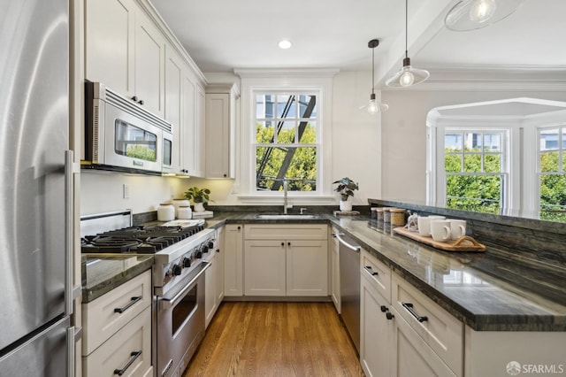 1856 Franklin St Unit 4, San Francisco, CA 94109 - kitchen featuring appliances with stainless steel finishes, a sink, light wood-style floors, dark stone countertops, and a peninsula