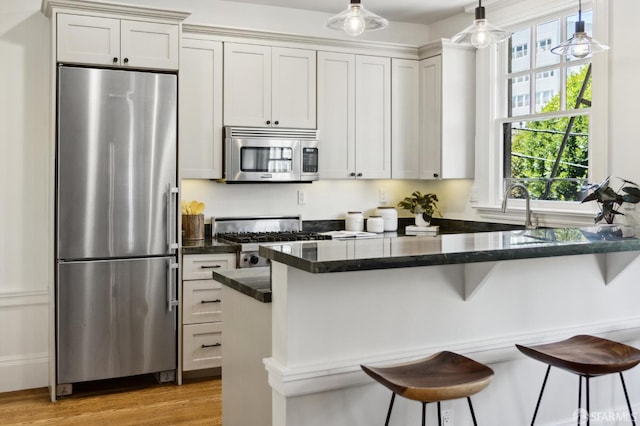 1856 Franklin St Unit 4, San Francisco, CA 94109 - kitchen featuring appliances with stainless steel finishes, a breakfast bar, light wood-style flooring, pendant lighting, and white cabinets