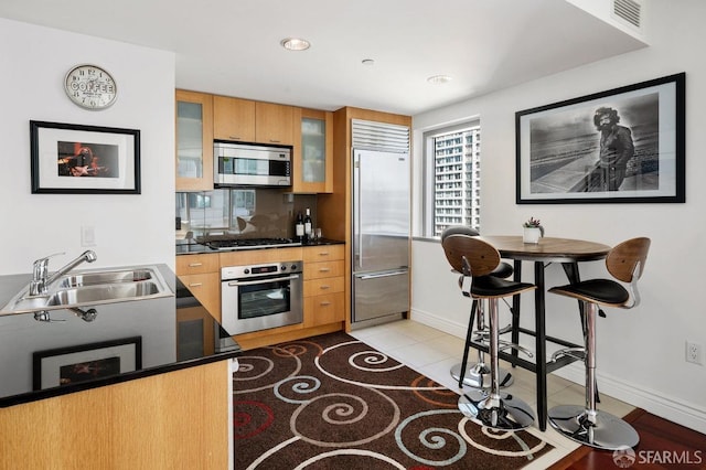 kitchen featuring sink, light tile patterned floors, stainless steel appliances, and a kitchen bar