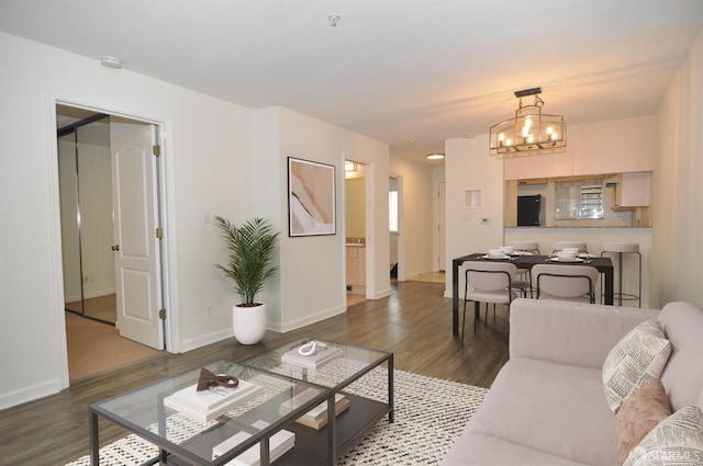 living room featuring an inviting chandelier, baseboards, and wood finished floors