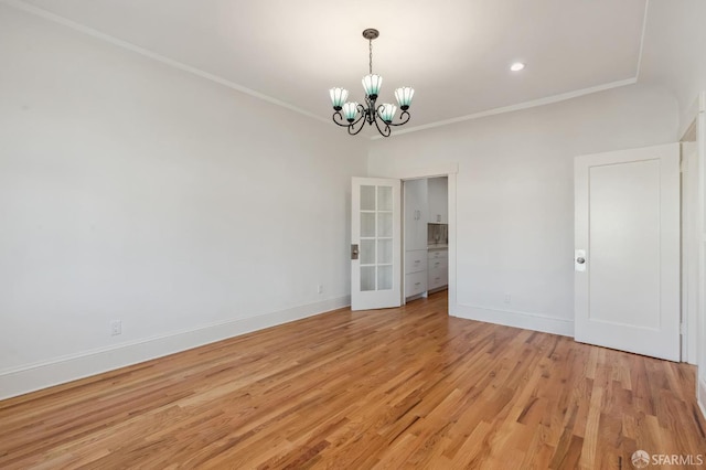 spare room featuring a notable chandelier, recessed lighting, baseboards, ornamental molding, and light wood-type flooring