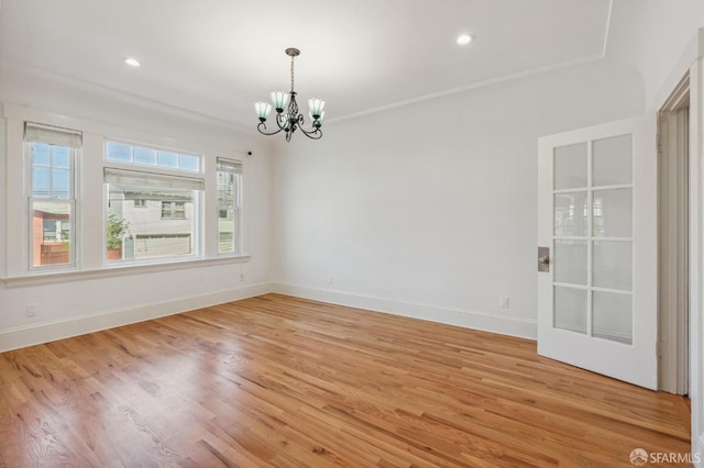 spare room featuring a chandelier, recessed lighting, light wood-style floors, and baseboards