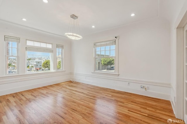 spare room with a chandelier, a wealth of natural light, light wood finished floors, and recessed lighting