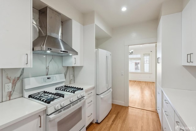 kitchen featuring light countertops, white appliances, white cabinetry, and wall chimney exhaust hood