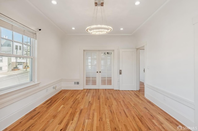 unfurnished room featuring french doors, light wood finished floors, recessed lighting, ornamental molding, and a chandelier