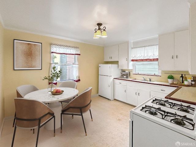 kitchen featuring white appliances, white cabinets, a kitchen breakfast bar, sink, and hanging light fixtures