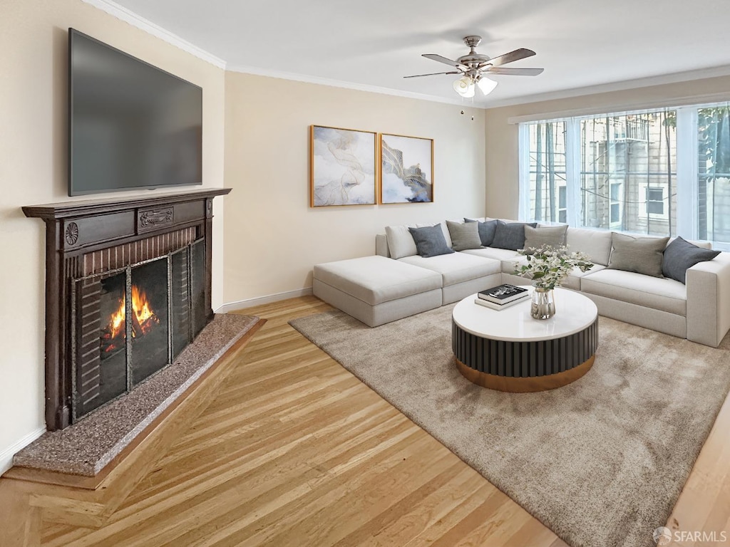 living room featuring ceiling fan, a fireplace, wood-type flooring, and ornamental molding