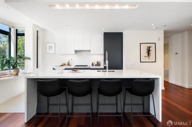 kitchen with a large island with sink, sink, white cabinets, and dark hardwood / wood-style floors