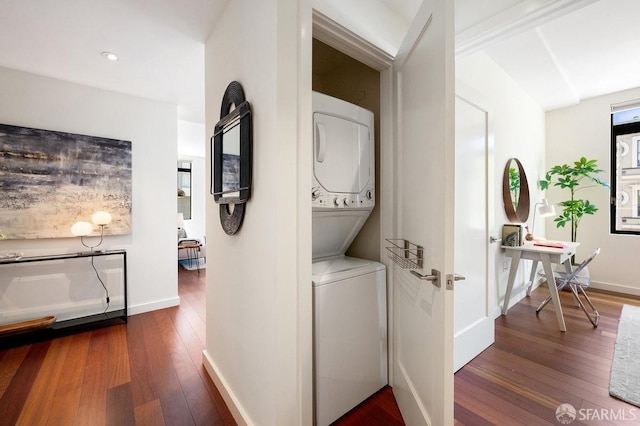 corridor with stacked washing maching and dryer and dark hardwood / wood-style floors