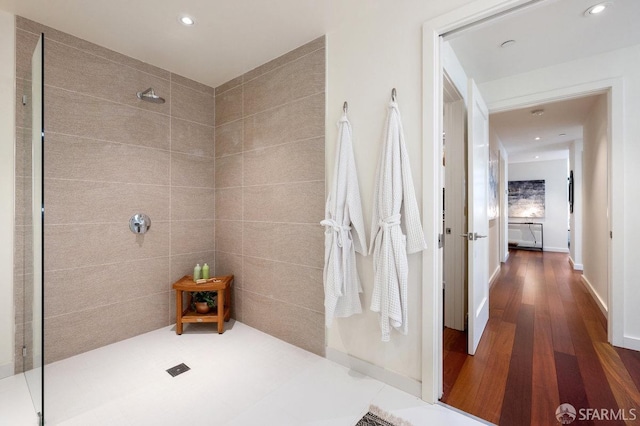 bathroom featuring hardwood / wood-style floors, tile walls, and tiled shower