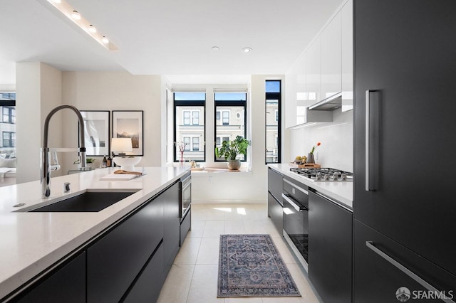 kitchen with sink, light tile patterned flooring, stainless steel appliances, white cabinets, and light stone counters