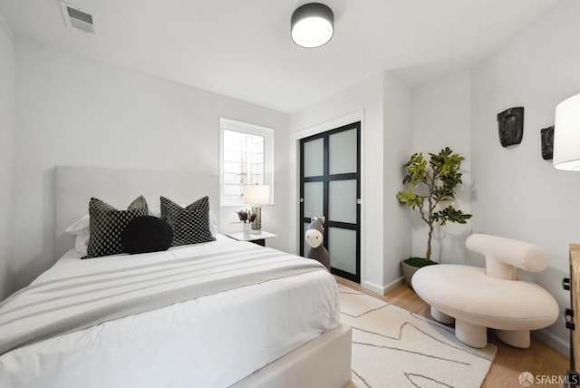 bedroom with baseboards, visible vents, and light wood-type flooring