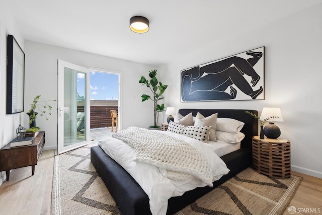 bedroom with access to exterior, wood finished floors, and baseboards