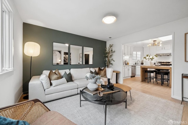 living room featuring an inviting chandelier, baseboards, and light wood finished floors