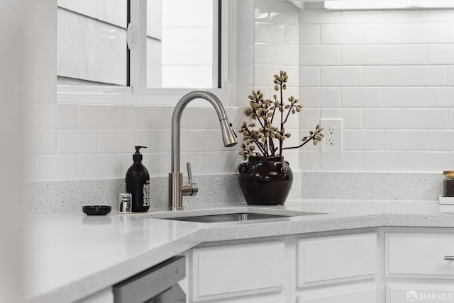 interior details with decorative backsplash, a sink, light stone counters, white cabinets, and dishwashing machine