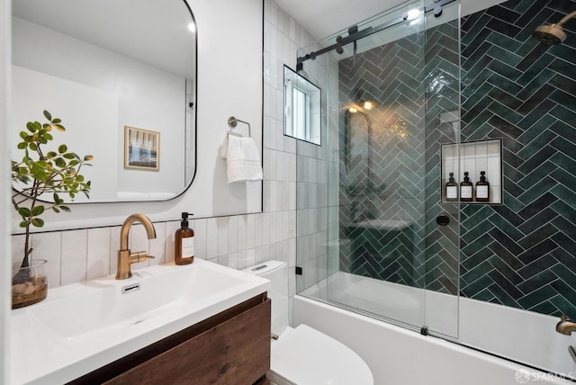 bathroom with combined bath / shower with glass door, toilet, tile walls, and vanity